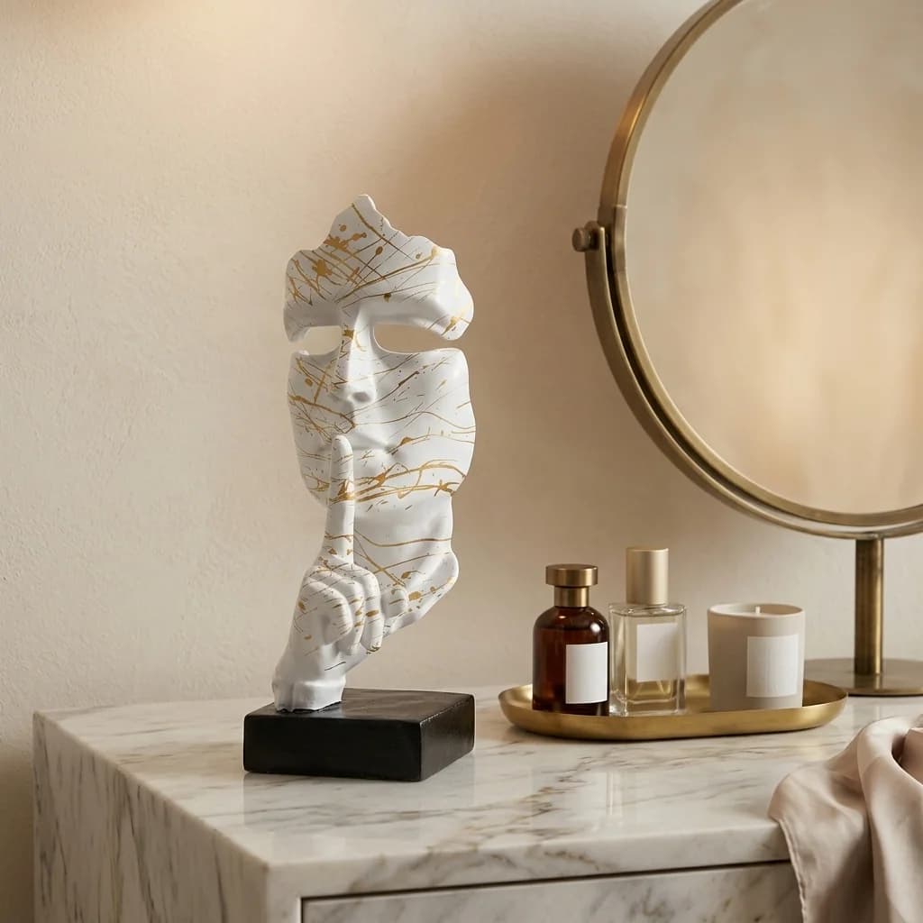 Wit gezicht masker sculptuur met gouden splash-accent op een marmeren kaptafel naast een messing spiegel en parfumflacons — Fourdomus decoratie voor een kaptafel of dressing.
